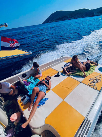 Travelers relaxing on a sunbed during a Blue Cave & Hvar Tour from Split, Croatia, enjoying the Adriatic sea on a modern speedboat