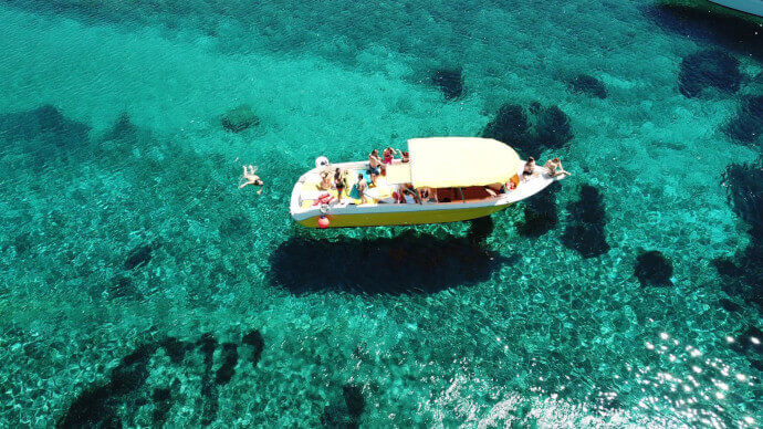 Yellow boat on crystal-clear blue waters in the Blue Lagoon, part of the Blue Cave & Hvar Tour from Split