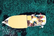 Drone shot of yellow speedboat on blue cave and lagoon tour